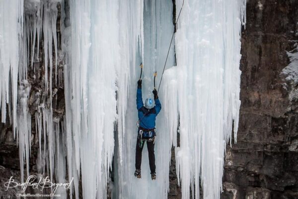 close up of climber making his way up ice chute in johnston canyon