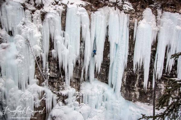 vast view of ice in johnston canyon with climber making his way up the cliff