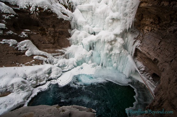 close up view of pool at bottom of frozen lower falls in johnston canyon in winter