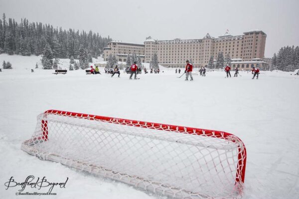 pond hockey net and players on ice at lake louise