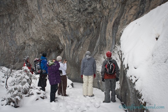 group-hikers-standing-ice-limestone-cliff-face-grotto-canyon-canmore-alberta-winter-outdoor-activity