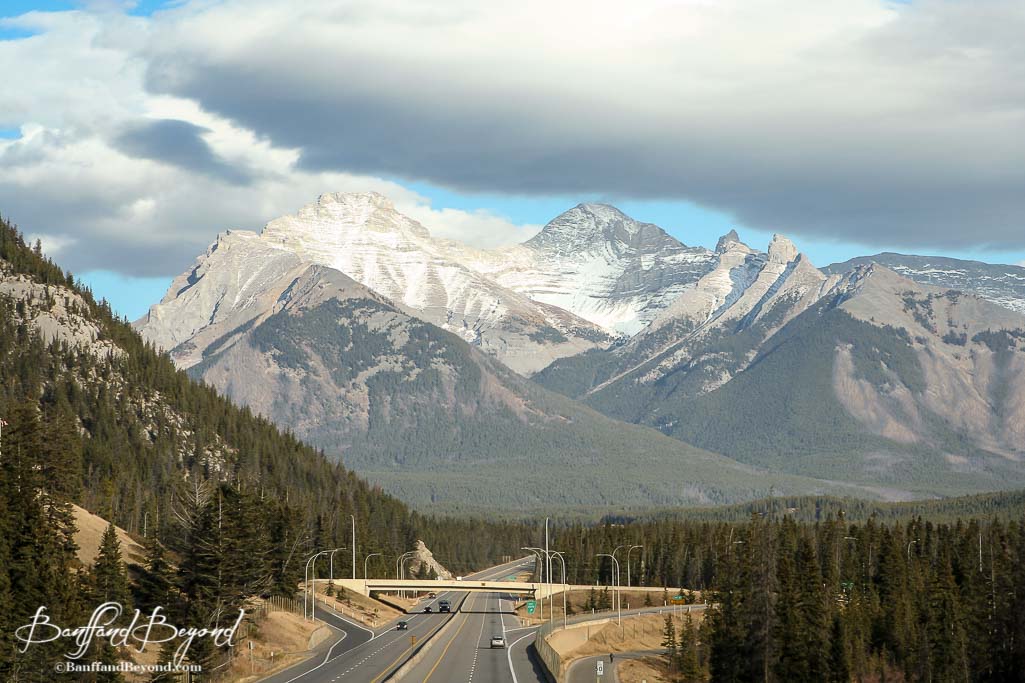 the trans canada highway in banff national park with towering mountains in the background