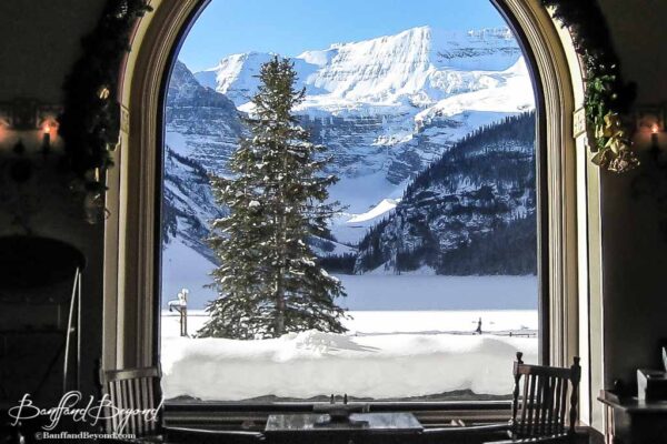 view of wintery lake louise from inside the fairmont chateau hotel restuaurant lounge