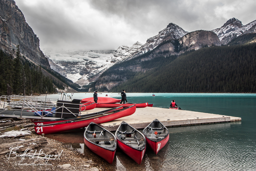 canoes sitting at the lake louise boat dock with victoria glacier in the background